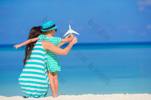 年轻女子和微型飞机在海滩的小女孩
