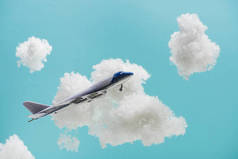 玩具飞机在白色蓬松的云彩中飞行，这些云彩是用蓝色孤立的棉毛制成的