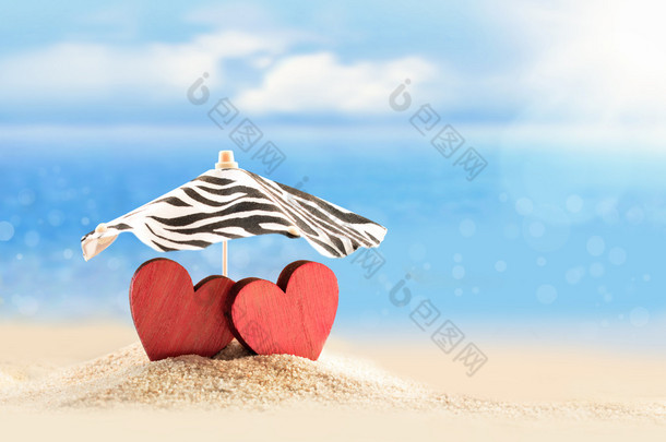在海滩上的雨伞下的两颗心。情人节那天.