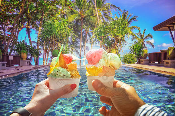 夫妇与<strong>美丽</strong>的明亮的甜意大利冰淇淋与不同的口味在手中。热带海滩全景的背景与椰子棕榈树。苏梅岛, 泰国