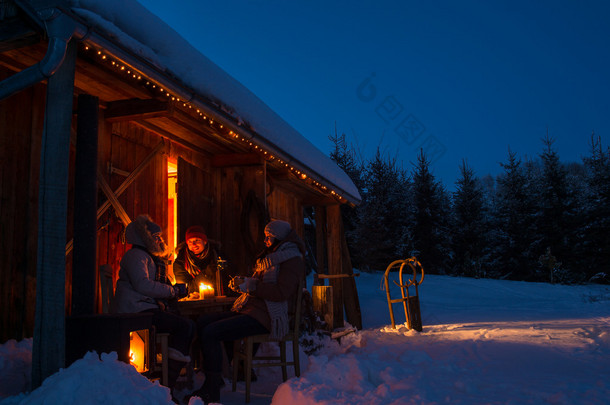 晚上冬季小屋朋友享受热饮料