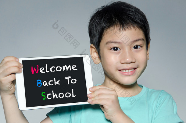 与平板电脑与回学校的<strong>小</strong>亚洲男孩微笑。