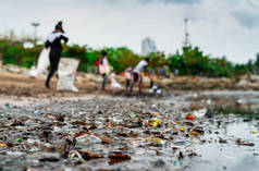 收集垃圾的志愿者的模糊。海滩环境污染。志愿者打扫海滩。整理海滩上的垃圾。海滩上有油渍。石油泄漏到海洋.
