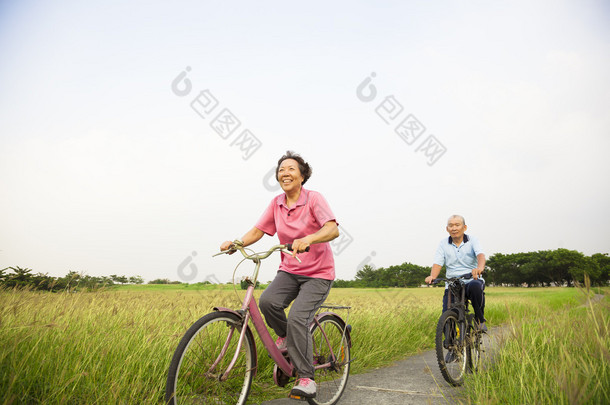 快乐亚洲老人老年人夫妇在公园与蓝色骑自行车 