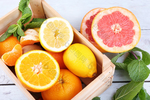 新鲜柑橘类水果，绿叶，木制木箱，色泽木制背景