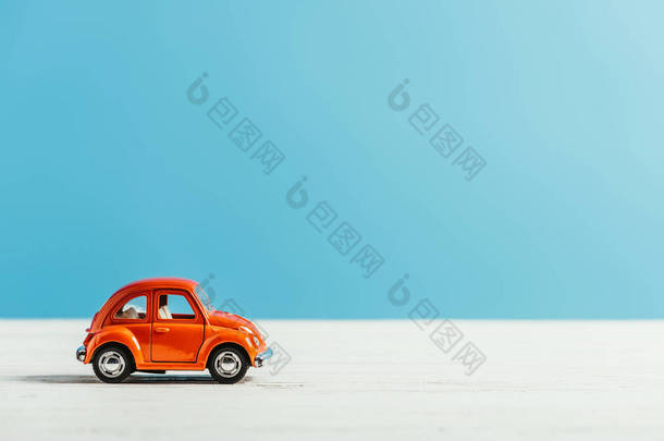 玩具红色汽车的侧视图骑在白色表面在蓝色背景
