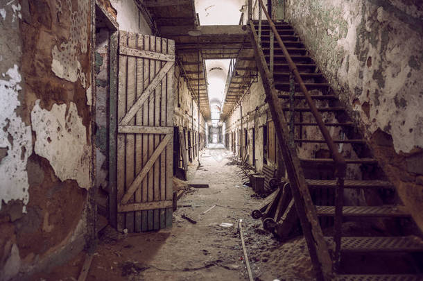 被遗弃的监狱细胞走道与旧生锈楼梯、 门和墙壁剥落。费城东州监狱.