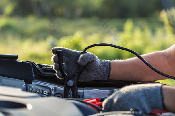 汽车技术人员持有电缆连接到电池的手