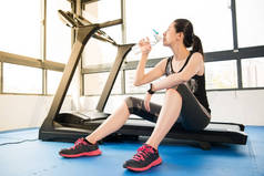 在跑步机上使用 smartwatch 饮用水体育女人休息一下