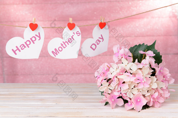 幸福的母亲一天消息写在纸做的爱心与粉红的底色上的花朵