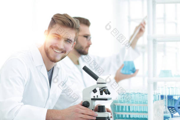 开展科学研究在实验室中用显微镜的男研究员