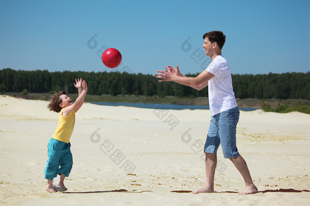 儿子对父亲的沙子上抛<strong>球</strong>