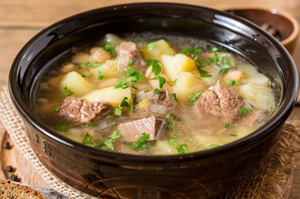 土豆、 豆类和韭葱石背景上的陶瓷碗里的<strong>牛肉汤</strong>.