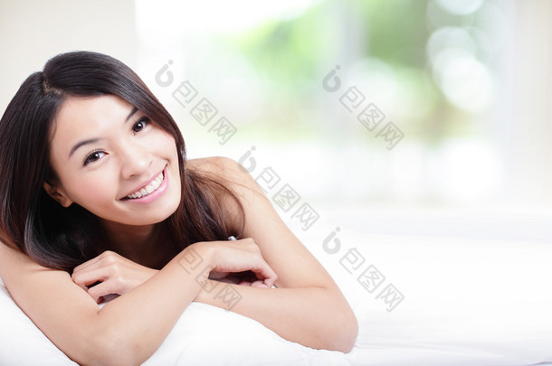 迷人的女人微笑脸和躺在床上
