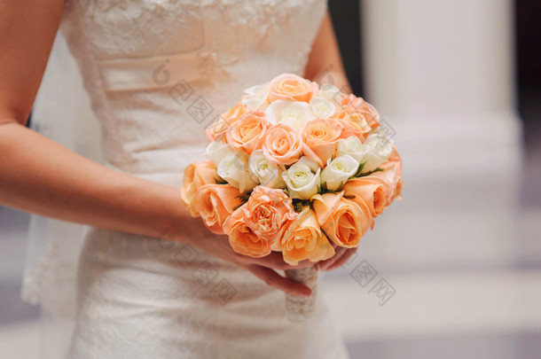 新娘紧握着白色和粉色的玫瑰的婚礼花束