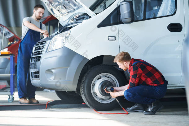 两名年轻的专业汽车维修技师在机库或车间为其中一辆汽车提供服务