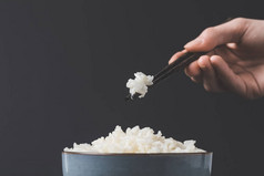 妇女用筷子从碗里拿刚熟的米饭
