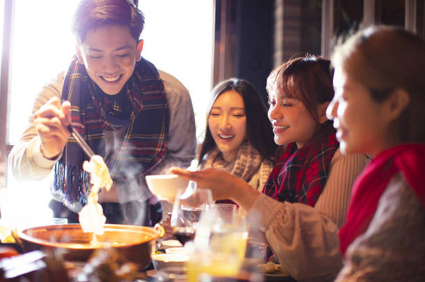快乐的年轻朋友在冬天在餐馆吃火锅