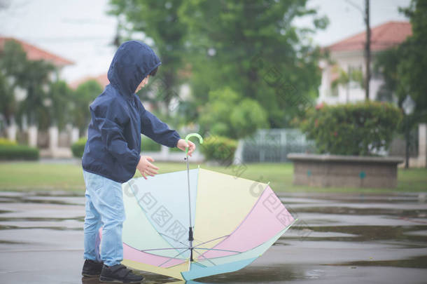快乐的亚洲男孩抱着五颜六色的伞，公园里玩