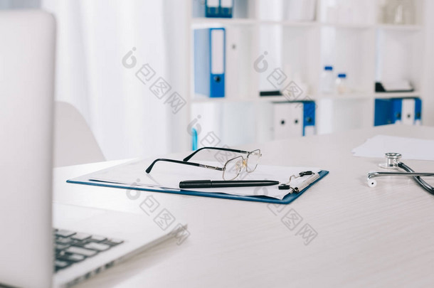 工作台上的眼镜和写字板上的钢笔