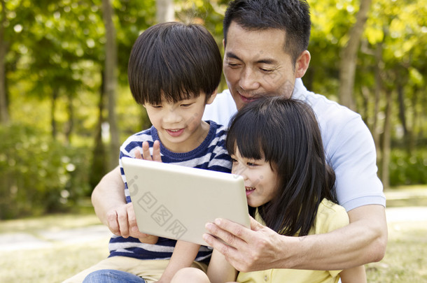 亚洲的父亲和儿童使用平板电脑在户外