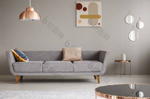 一个简单的沙发与枕头在<strong>客厅装饰</strong>铜灯, 镜子和绘画的真实照片