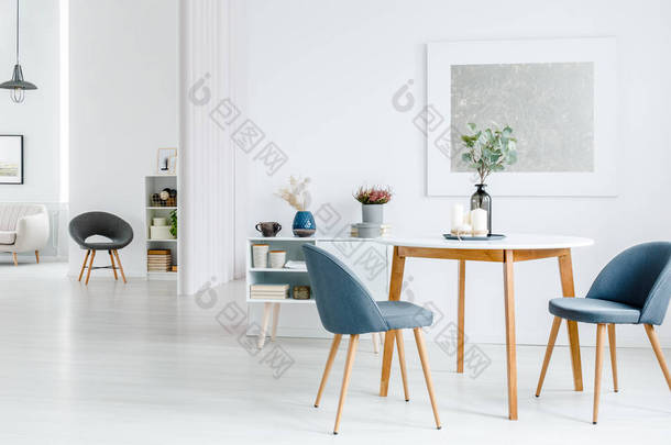 灰色椅子在木桌反对白色墙壁与<strong>银色</strong>绘画在公寓内部