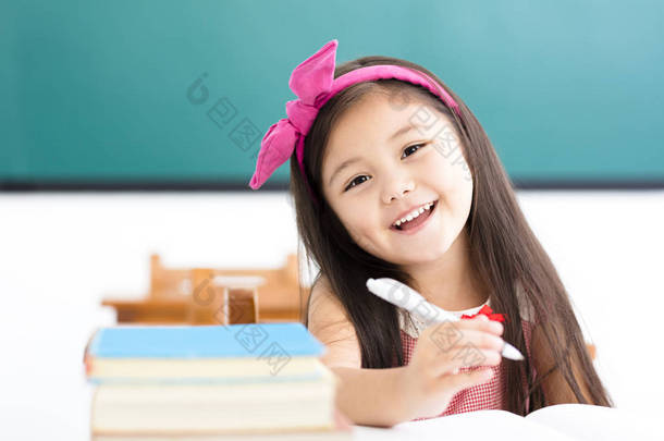 快乐的小女孩在教室里的桌子上写东西