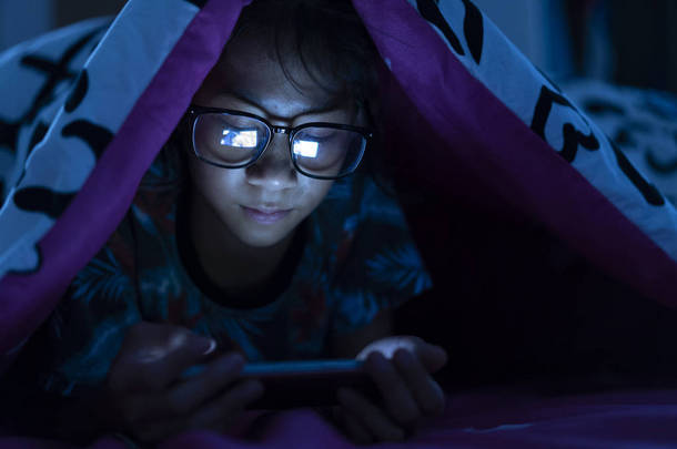 女孩戴着眼镜在卧室的黑<strong>床上</strong>使用手机