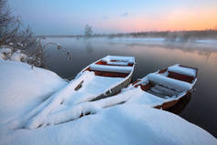 美丽的冬日日出在河边. 雪中的船