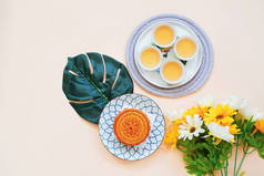 中国月饼与热茶和花卉在黄色背景, 节日和节日概念的顶部视图