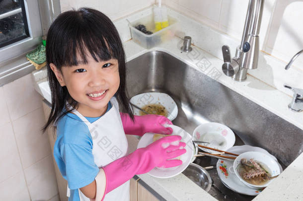 亚洲的中国小女孩在厨房里洗盘子