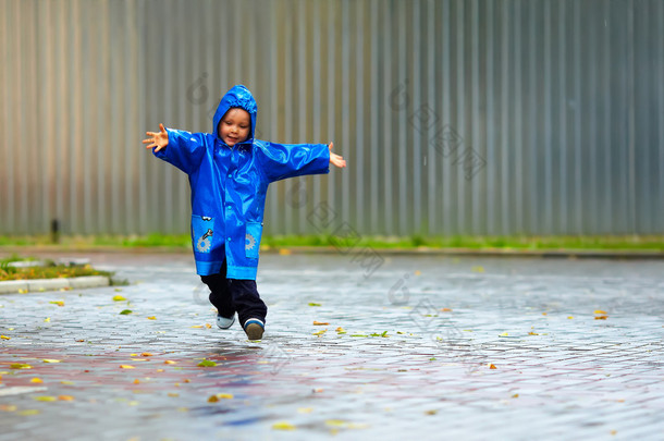 开心宝贝男孩运行的街头、 多雨的天气