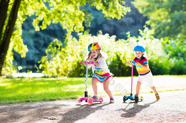 孩子们骑着滑板车中夏公园.