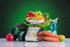 绿色的鳞片、哑铃和水瓶上的新鲜水果和蔬菜特写视图