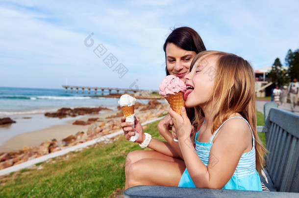 妈妈和女儿享受海滩的冰激凌