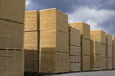  木材工业-成品木材对天空。成堆的加工木板