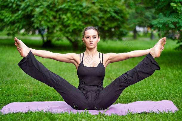 瑜伽。在公园里练习瑜伽冥想的年轻女子。健康生活方式概念