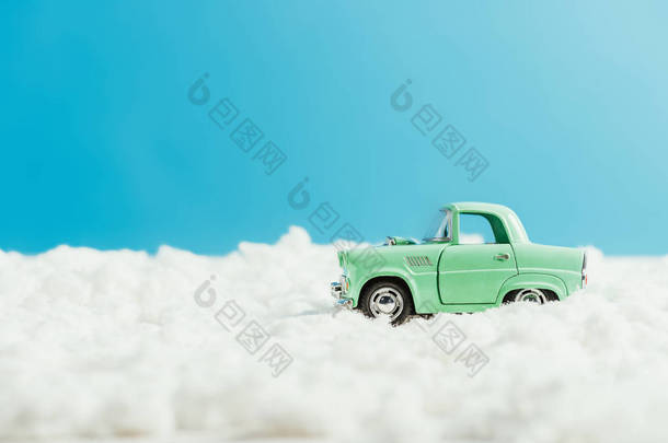 在蓝色背景上由棉花制成的雪骑玩具汽车的侧视图