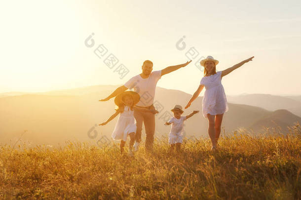 快乐的家庭: 母亲, 父亲, 孩子的儿子和女儿在自然日落
