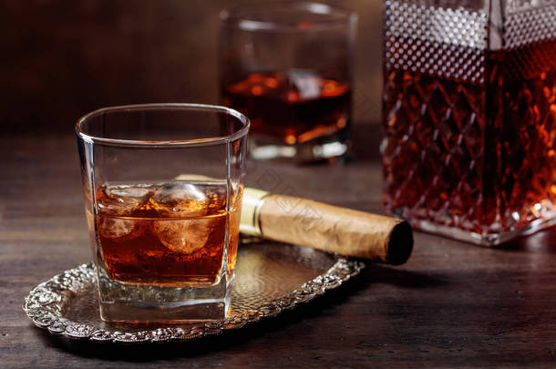 旧木桌上的威士忌和雪茄杯.