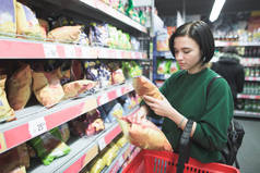 一个小女孩在超级市场买零食。这个女孩在超市里选择薯条, 把它们放在一个红色的购物车里。在超级市场购物.