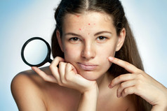 Girl with a pimply face holding magnifying glass. Woman skin care concept