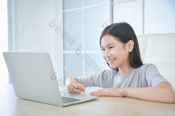 十几岁以下的亚洲女学生在家里带着笔记本电脑上网学习。儿童的教育和远距离学习。检疫期间的家教. 