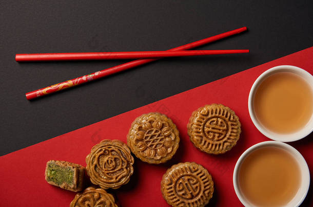 红色和<strong>黑色背景</strong>上的传统中国月饼与筷子的顶部视图