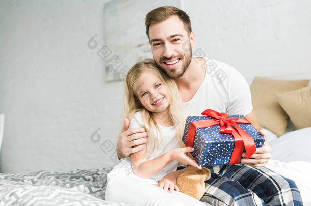 幸福的父亲和女儿拿着礼品盒和微笑着在相机