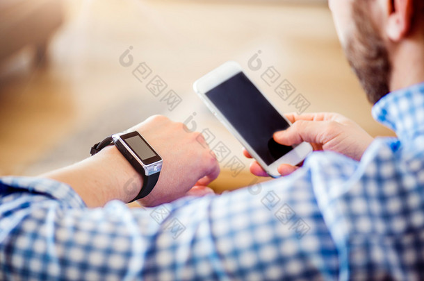 不可识别的人在家里使用智能手机和智能手表