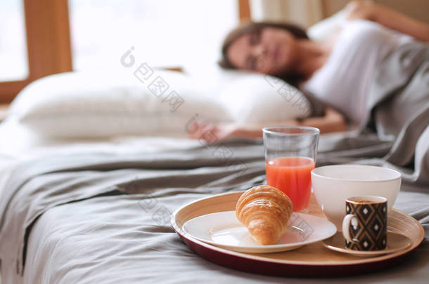 与咖啡和牛角面包吧，年轻漂亮的女人床上早餐