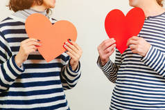 情人节情侣。 女孩和她的男朋友抱着两个纸心。 坠入爱河吧 情人节快乐