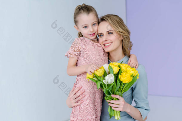妇女举行花束和拥抱可爱的女儿的女人的日子